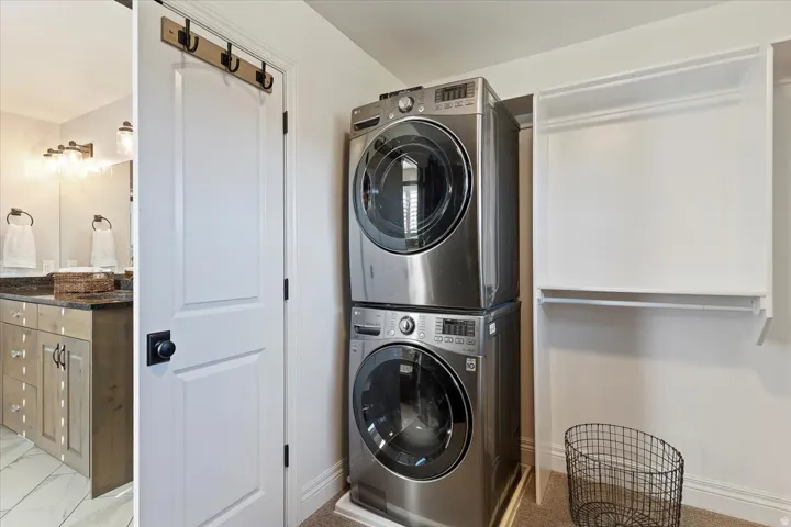 Stackable washer and dryer, built-in shelving, white paneled door, black hardware, wood-finish vanity