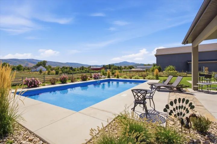 Rectangular in-ground swimming pool with a concrete surround, an adjacent covered patio, and a mountain backdrop