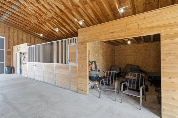 Exposed wood ceiling beams, wood-paneled walls, concrete flooring, and built-in wood stalls with metal accents