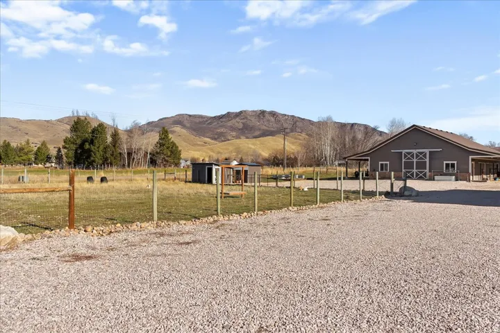 Expansive gravel parking area, fenced pasture, and a barn-style structure with a covered porch
