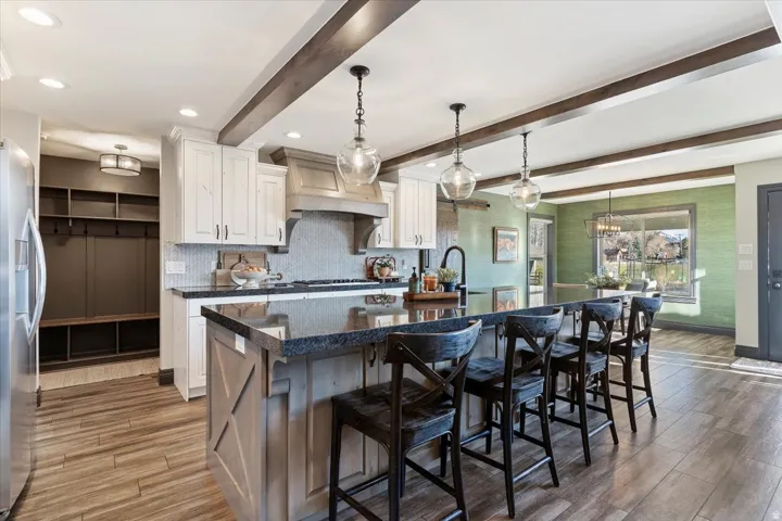 Kitchen featuring an expansive island with a dark countertop, overhead pendant lighting, and wood-finish flooring