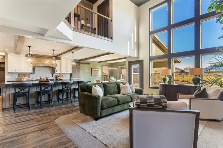 Two-story living area with soaring windows, wood-finish flooring, and exposed ceiling beams
