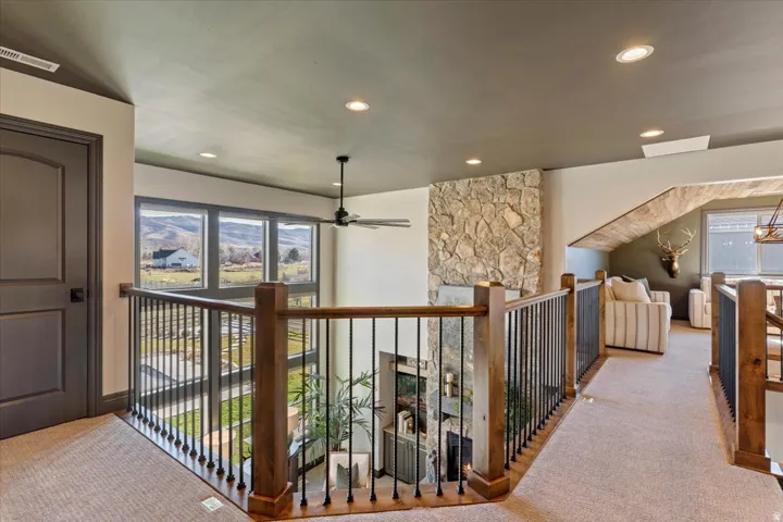 Upper landing featuring recessed lighting, a ceiling fan, a stone-clad wall, and an open railing with wood and metal balusters