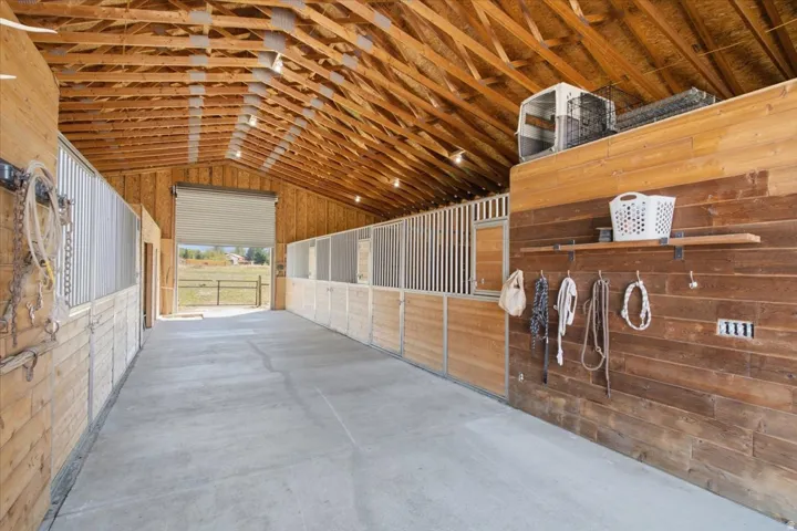 Exposed wood beam ceiling, concrete flooring, recessed lighting, roll-up door access, and wood-paneled walls