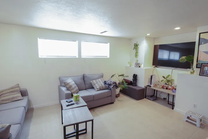 Recessed lighting, light-toned walls, two high-set windows, and large format floor tiles