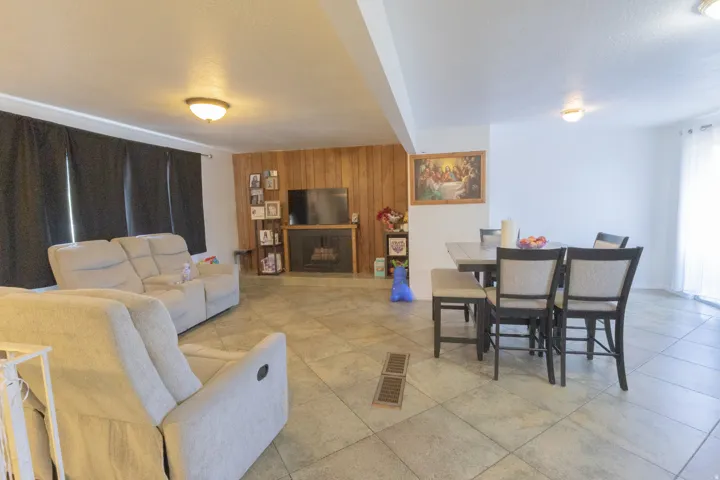 Spacious interior featuring tile flooring, a built-in fireplace, wood paneling, and ceiling-mounted light fixtures