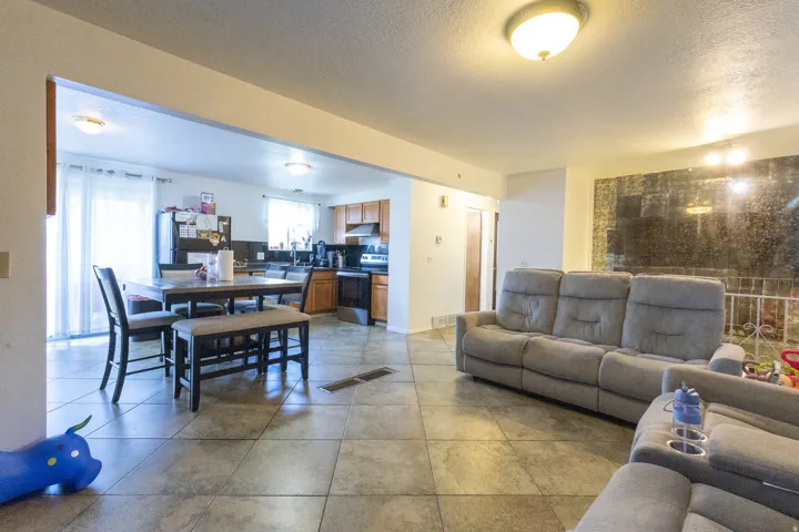 Open-concept living space featuring ceramic tile flooring, a kitchen with wood-finish cabinetry, and a dining area with a sliding glass door