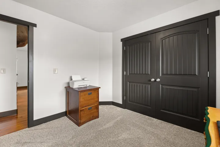 Wall-to-wall carpeting, black trim, and a built-in double-door closet with polished hardware