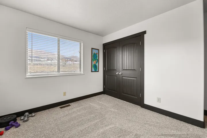 Textured carpeting, white painted walls, dark wood-finish trim, and a double-door closet with arch paneling