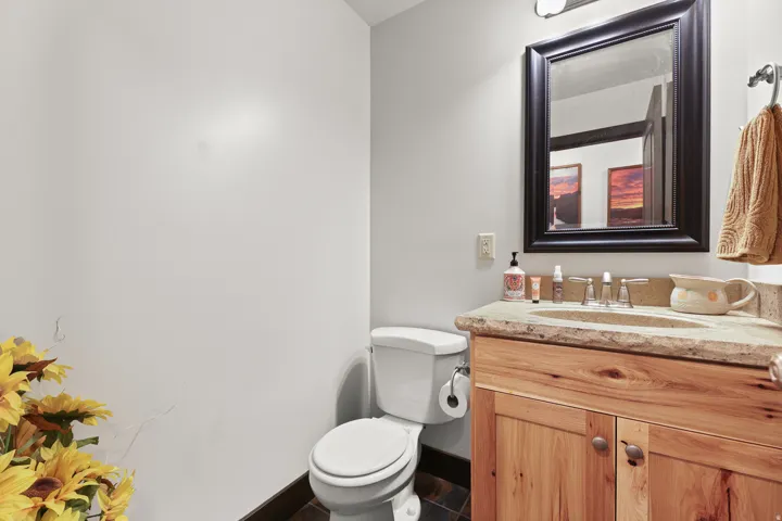 Stone countertop with integrated sink, wood-finish vanity, framed mirror, and tiled flooring