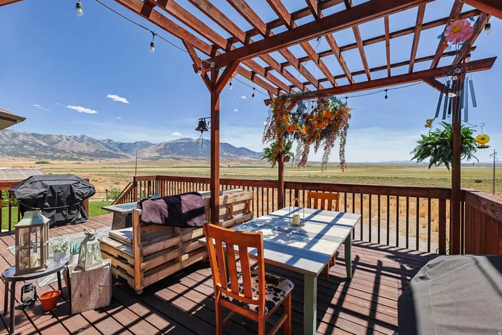 Expansive outdoor deck featuring a wooden pergola, string lighting, and a full perimeter railing