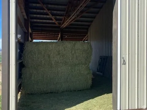 Metal-sided barn structure with a sliding door, exposed wood beam framing, and a corrugated metal roof