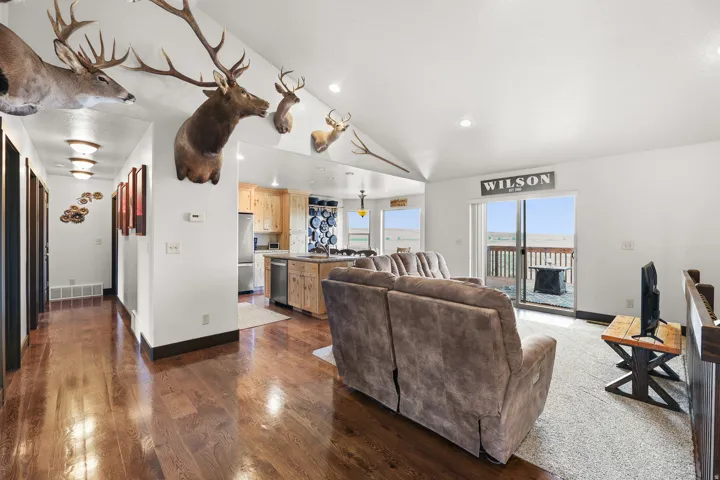 Vaulted ceiling with recessed lighting, wood-finish flooring, and white walls