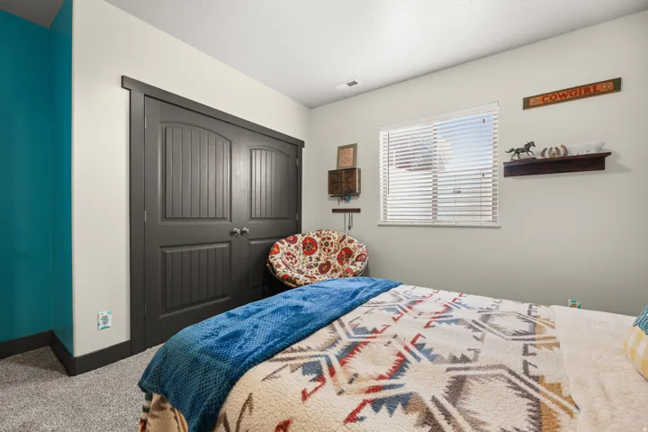 Built-in closet with dark paneled doors, light grey wall, teal accent wall, and a window with blinds