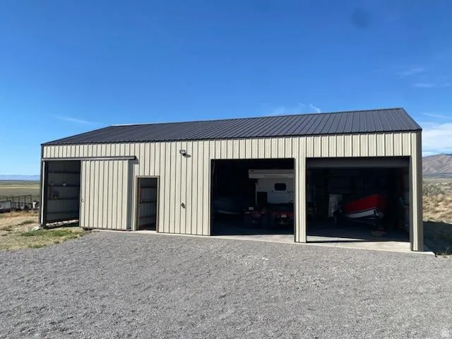 Corrugated metal siding with a dark metal roof, multiple garage bays, and a gravel driveway