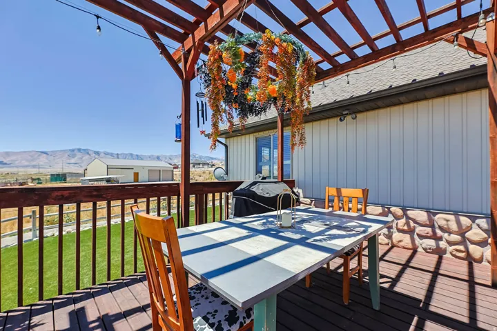 Spacious wood-finish deck with a pergola, stone foundation accent, and durable siding