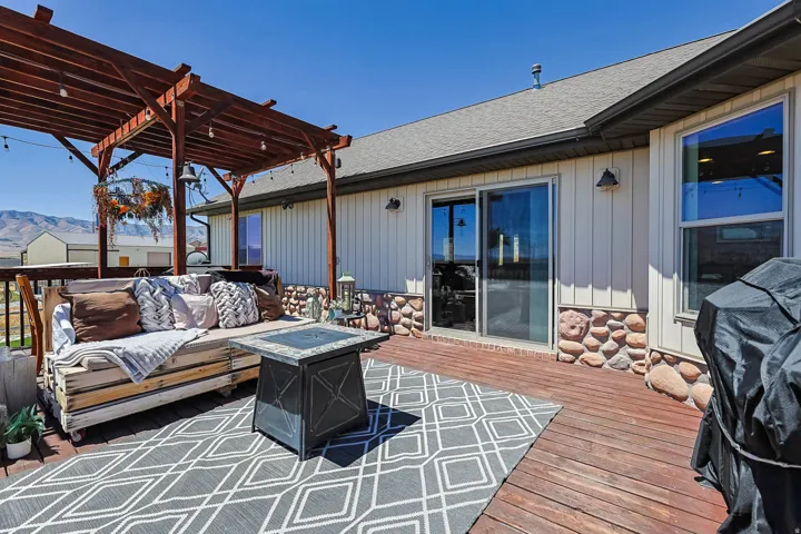 Expansive wood deck with a built-in pergola, offering a sliding glass door entry to the interior