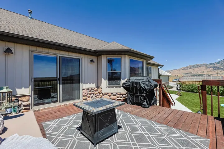 Expansive wood deck with a built-in fire pit, featuring sliding glass doors and bay windows