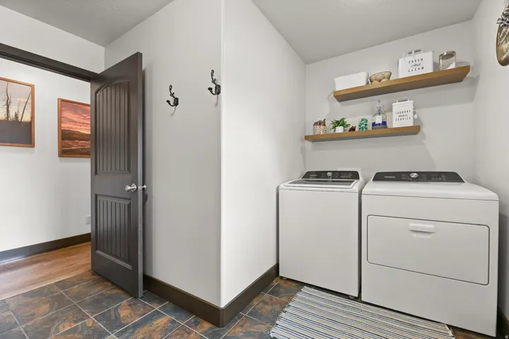 Laundry area featuring a tile floor, two floating wood shelves, and a dark wood-paneled door