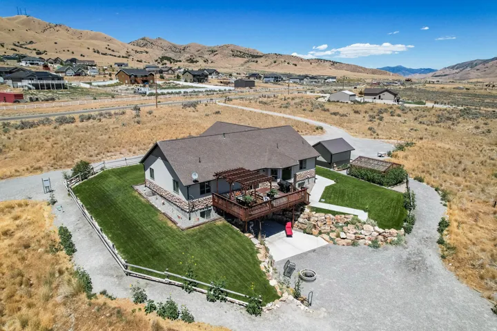 Two-story residence with a stone and siding exterior, expansive rear wood deck with a pergola, and a detached shed