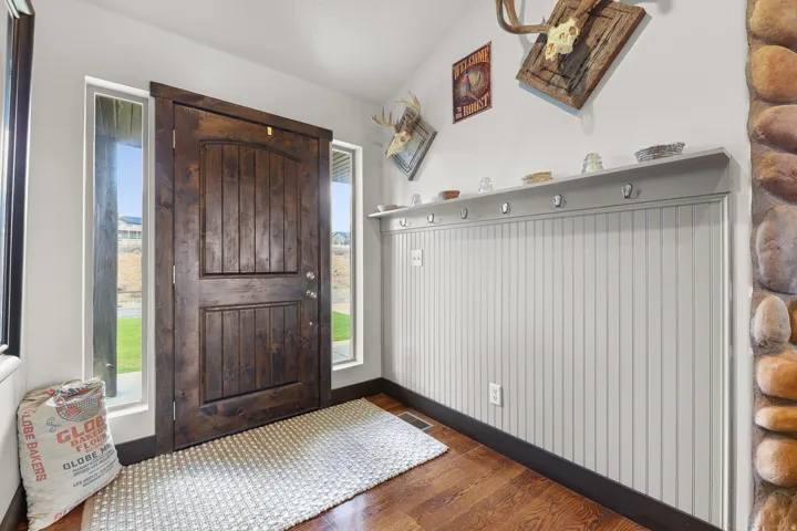 Wood-finish flooring, dark wood entry door, and vertical window accents