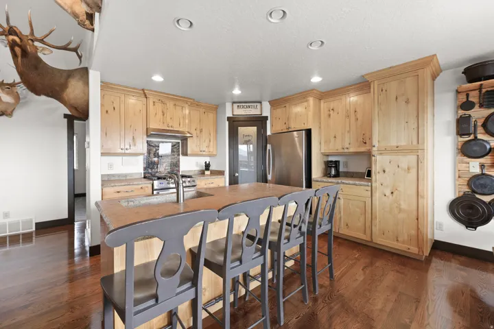Kitchen featuring wood-finish flooring, recessed lighting, wood cabinetry, stainless steel appliances, and a central island with integrated sink