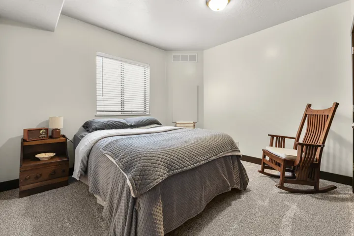Carpeted flooring, neutral wall tones, window with horizontal blinds, and a flush mount ceiling light