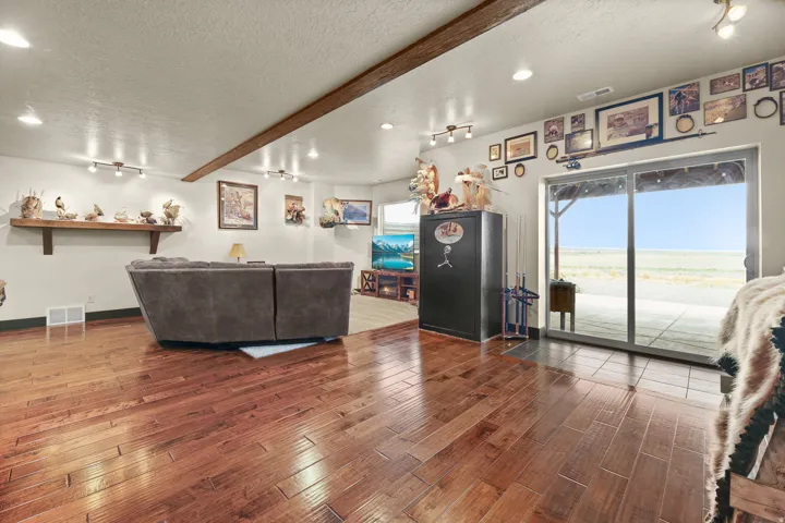 Open-concept living space showcasing refinished wood-finish flooring, recessed lighting throughout, and expansive glass sliding doors framing panoramic landscape vistas