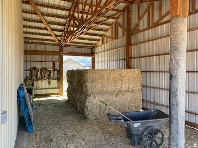 Open-air barn structure featuring a corrugated metal roof and exposed wood beam construction