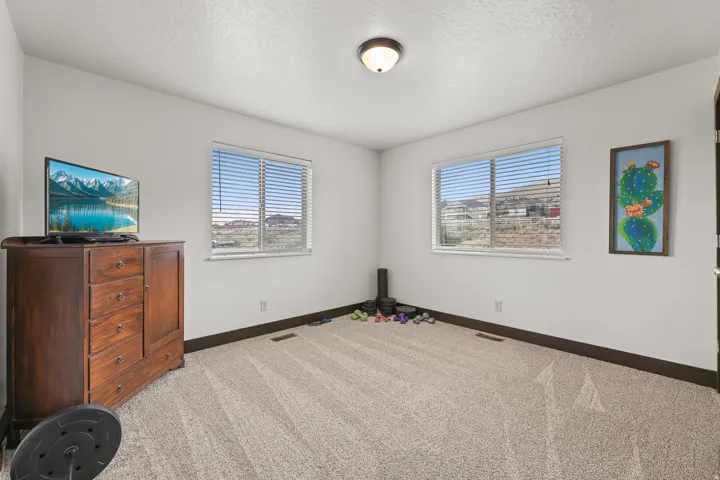 Neutral wall tones, recessed lighting fixture, carpeted flooring, and two windows with horizontal blinds
