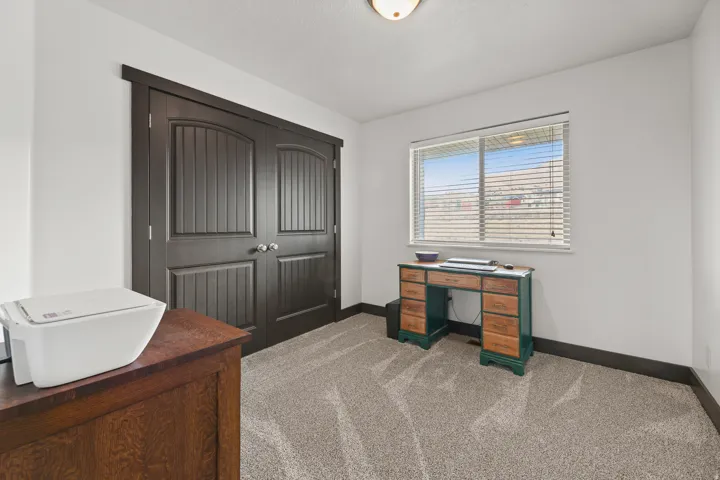White walls with dark trim, carpeted flooring, and a window with blinds