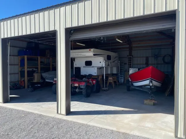 Corrugated metal siding with two large bays, concrete flooring, and exposed beam ceiling