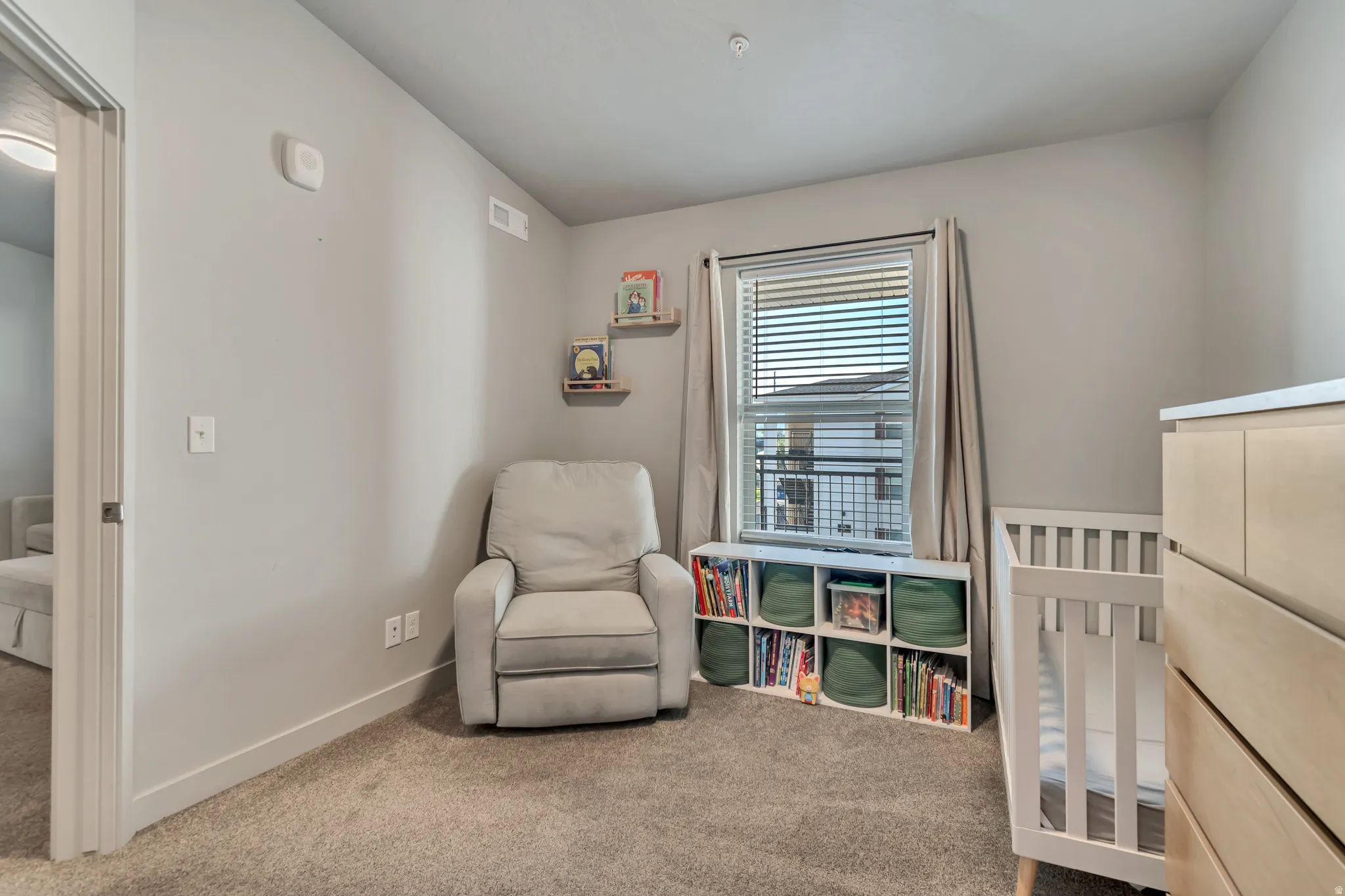 Carpeted room featuring a window with horizontal blinds, built-in shelving, and a neutral wall color