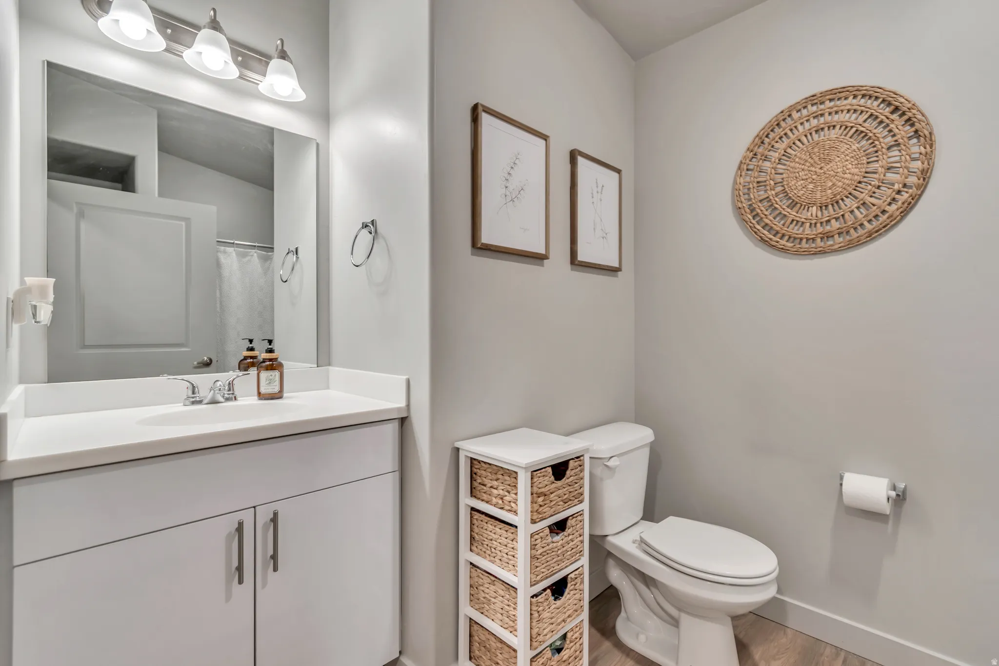 Vanity with a white countertop and integrated sink, chrome faucet, and overhead three-bulb vanity lighting