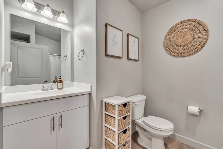 Vanity with a white countertop and integrated sink, chrome faucet, and overhead three-bulb vanity lighting