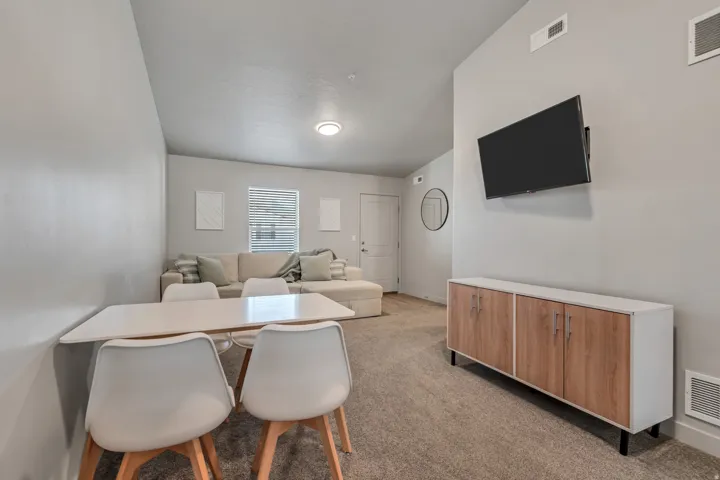 Vaulted ceiling, neutral wall color, carpeted flooring, wall-mounted display, built-in shelving with wood-finish doors