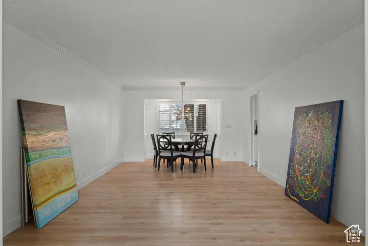 Recessed window with plantation shutters, wood-finish flooring, white baseboards, crown molding, and a ceiling-mounted light fixture