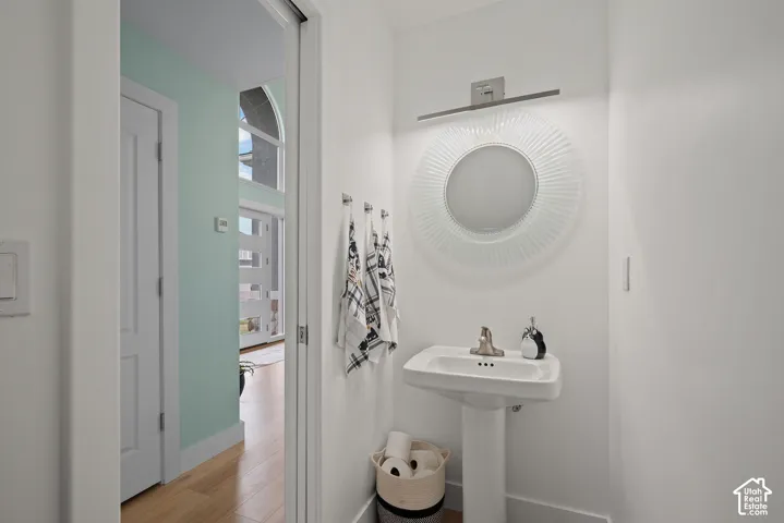 Pedestal sink with polished chrome faucet, illuminated by a linear light fixture above a decorative mirror