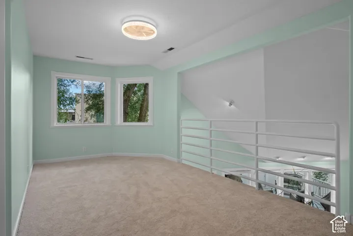 Carpeted loft space with a modern flush-mount light fixture