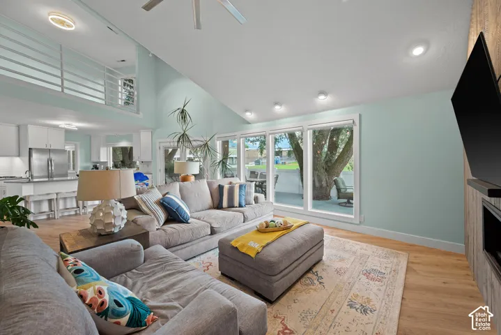 Vaulted ceiling, wood-finish flooring, recessed lighting, expansive windows, and a built-in media console