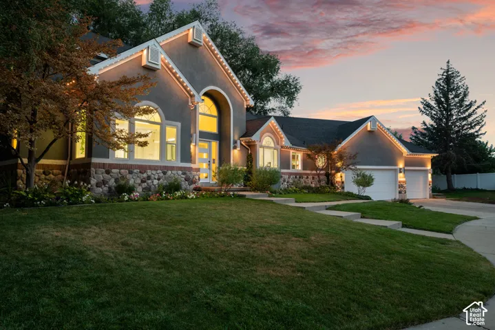 Stucco exterior with stone accents, arched windows, prominent gables, and an attached two-car garage