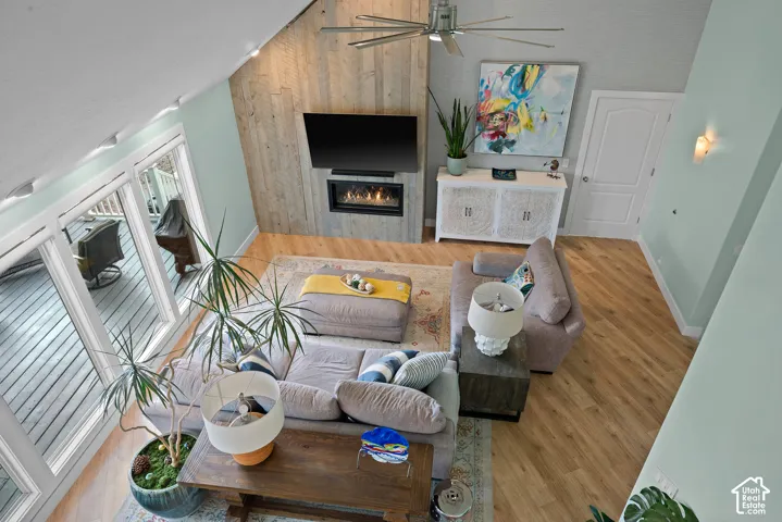 Vaulted ceiling with an exposed wood-finish accent wall, modern electric fireplace, and wood-finish flooring