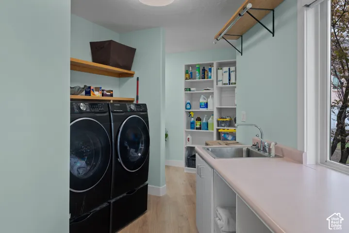 Dedicated laundry area with light wood-finish flooring, built-in shelving, and a utility sink