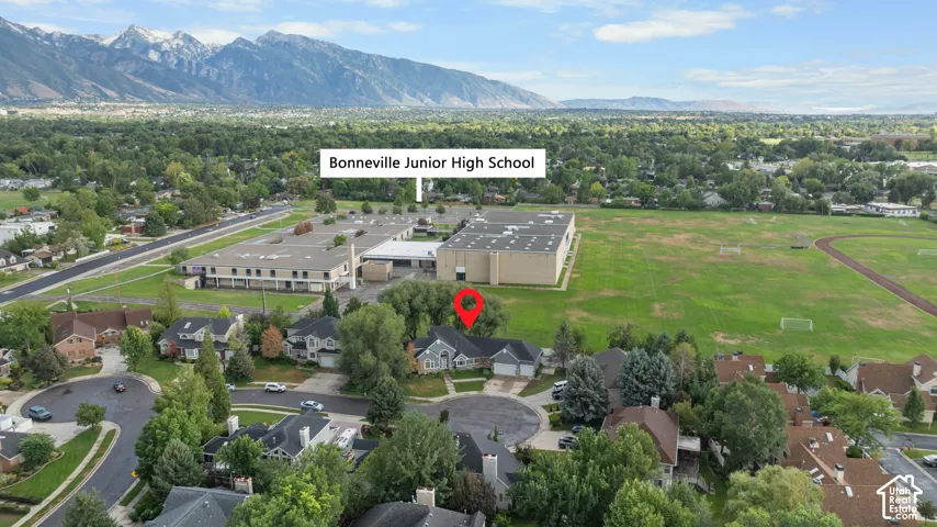 Aerial overview showcasing a residential neighborhood with mature trees, a cul-de-sac, and proximity to a school facility