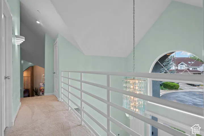 Hallway featuring a vaulted ceiling, arch window with decorative grilles, and contemporary railing