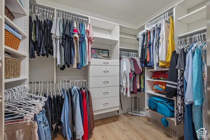 Custom closet system featuring multiple hanging rods, built-in shelving, integrated drawers with modern pulls, and wood-finish flooring