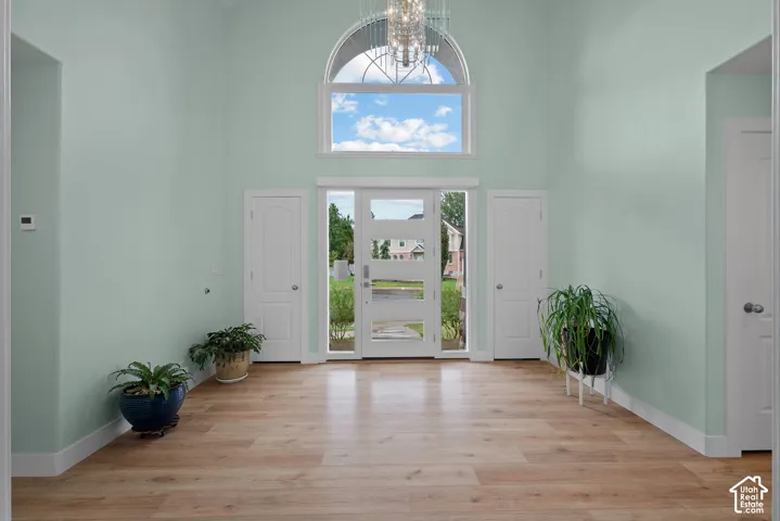 Two-story entryway with wood-finish flooring, a contemporary chandelier, arched transom window, and a glass-paneled entry door