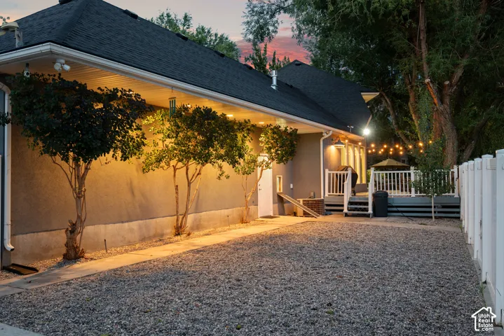 Exterior featuring stucco siding, gravel hardscaping, a multi-level deck with white railings, and mature trees