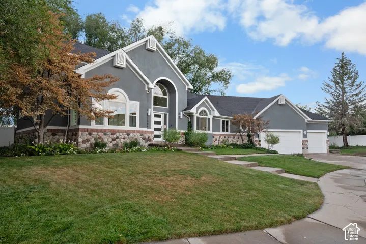 Stucco exterior with stone accenting, arched window features, and multiple garage doors