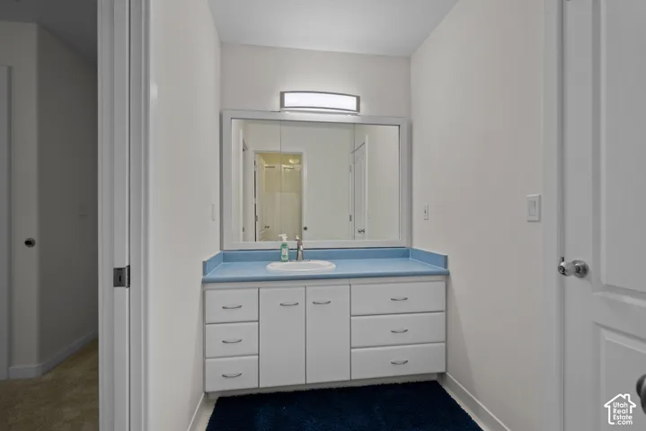 Vanity with integrated sink, expansive mirror, and built-in cabinetry featuring multiple drawers